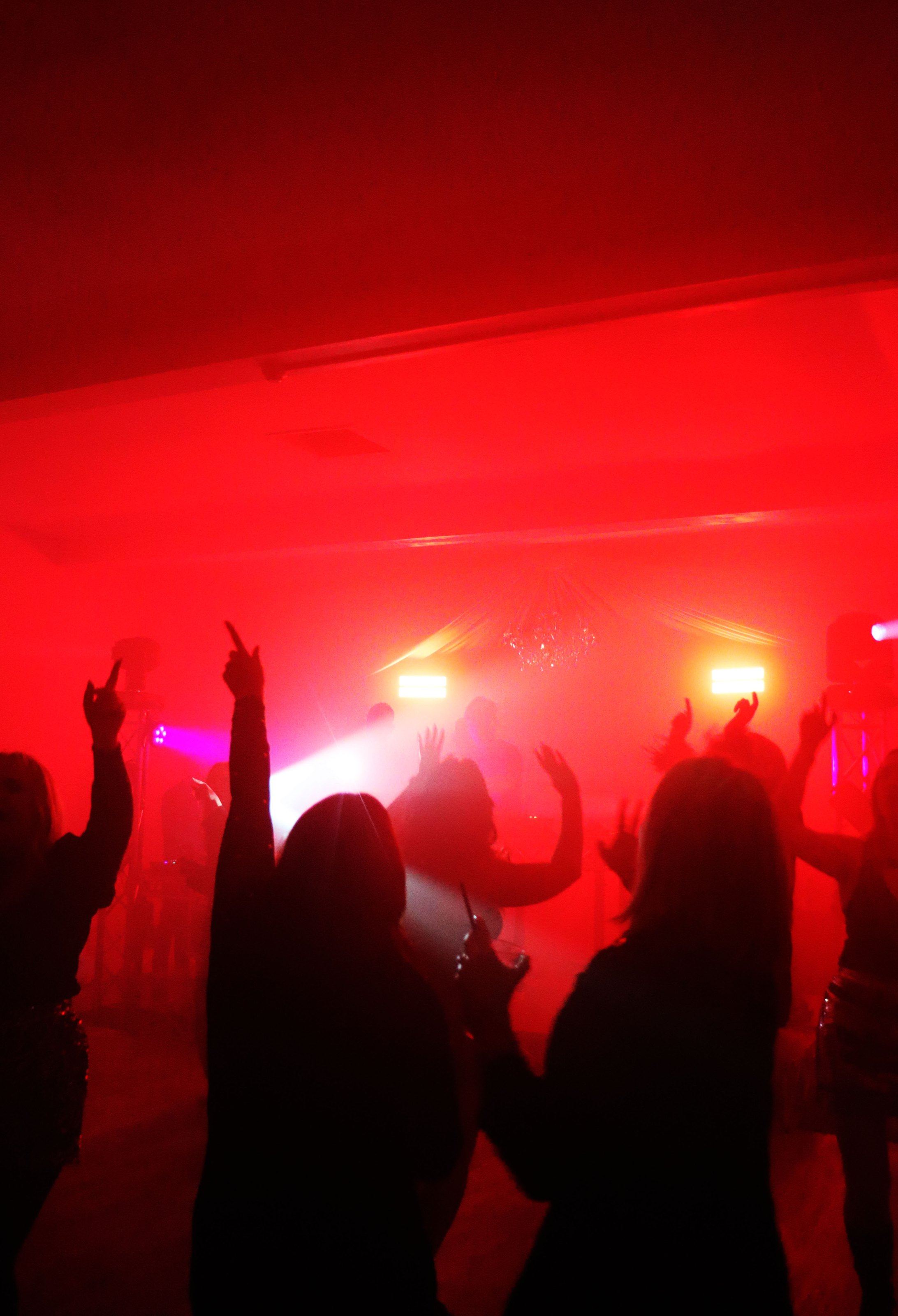 Dancers with hands raised under red lights at The Xmas Crackers, The Carlton, Newcastle-under-Lyme